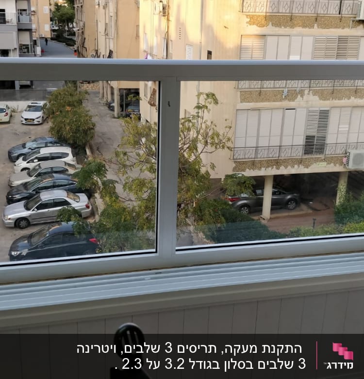 חלון אלומיניום עם נוף חיצוני של חניה ובניינים